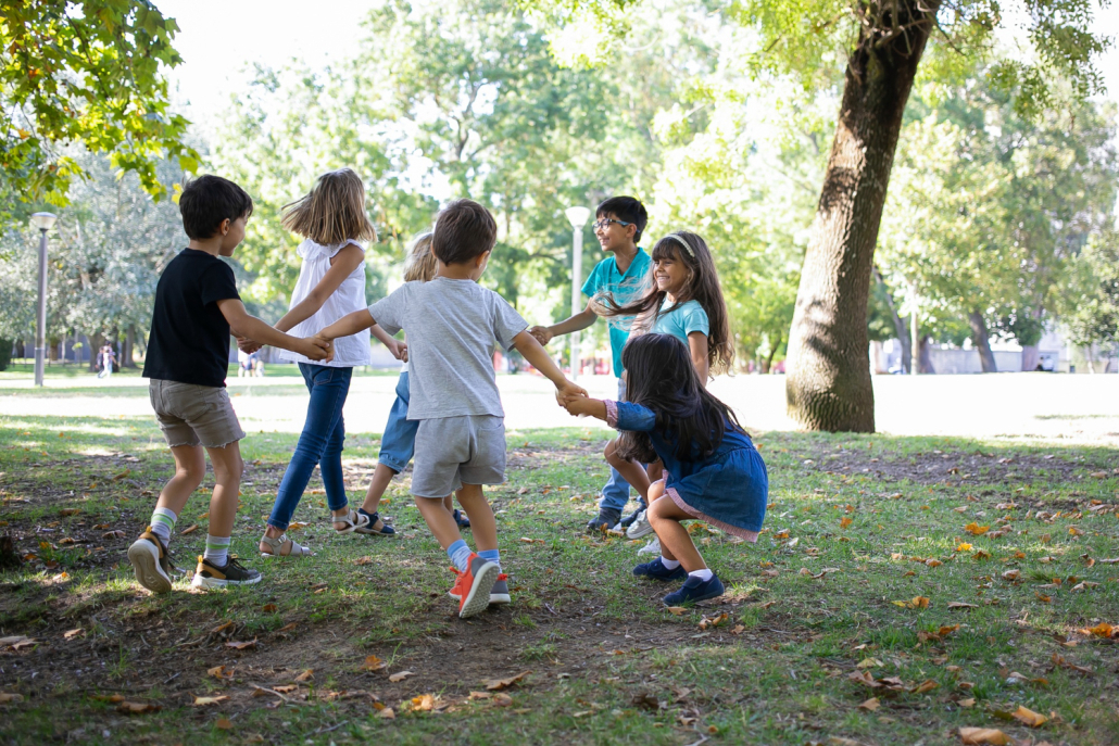 ninos felices jugando juntos al aire libre bailando sobre cesped disfrutando actividades al aire libre divirtiendose parque concepto fiesta o amistad ninos